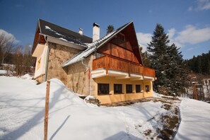 A two-story chalet with a wooden balcony, stone walls, and a snow-covered landscape. - Star Hamry Mosl590 (Staré Hamry)