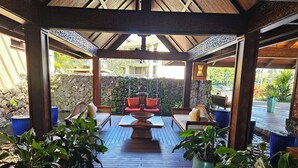 Zona de estar exterior con mobiliario de madera y plantas en macetas.