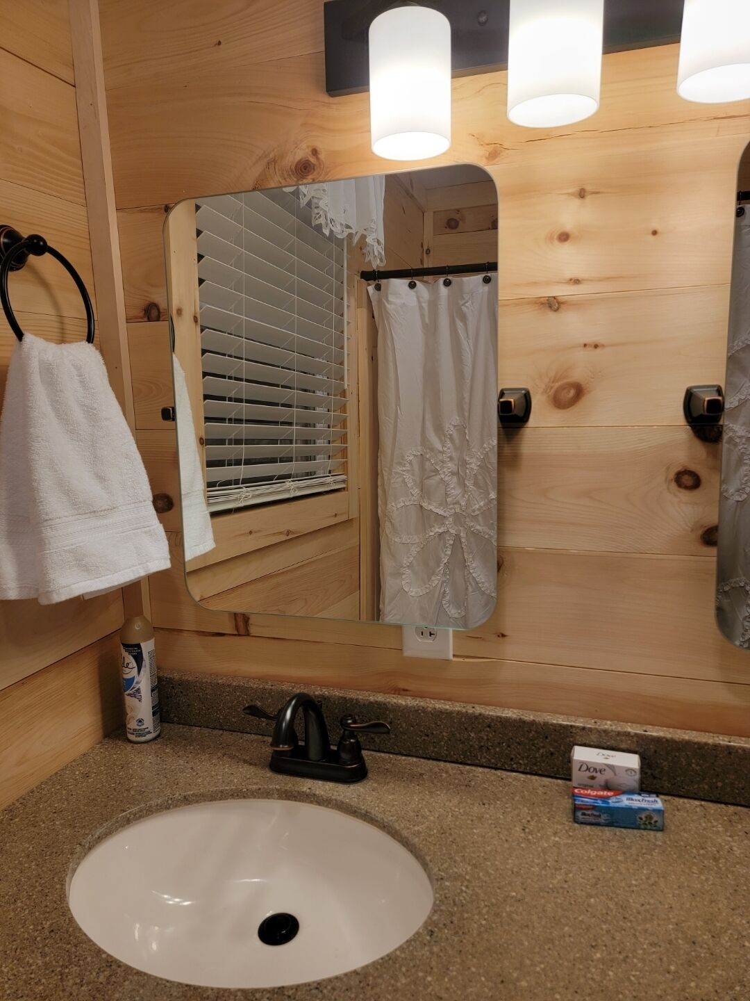 A bathroom with a wooden interior, a white sink, a mirror, a towel, and a bottle of Dove soap.