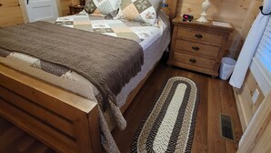 Ein Schlafzimmer im Chalet-Stil mit einem Bett, Nachttischen, einer Lampe und einem Teppich.