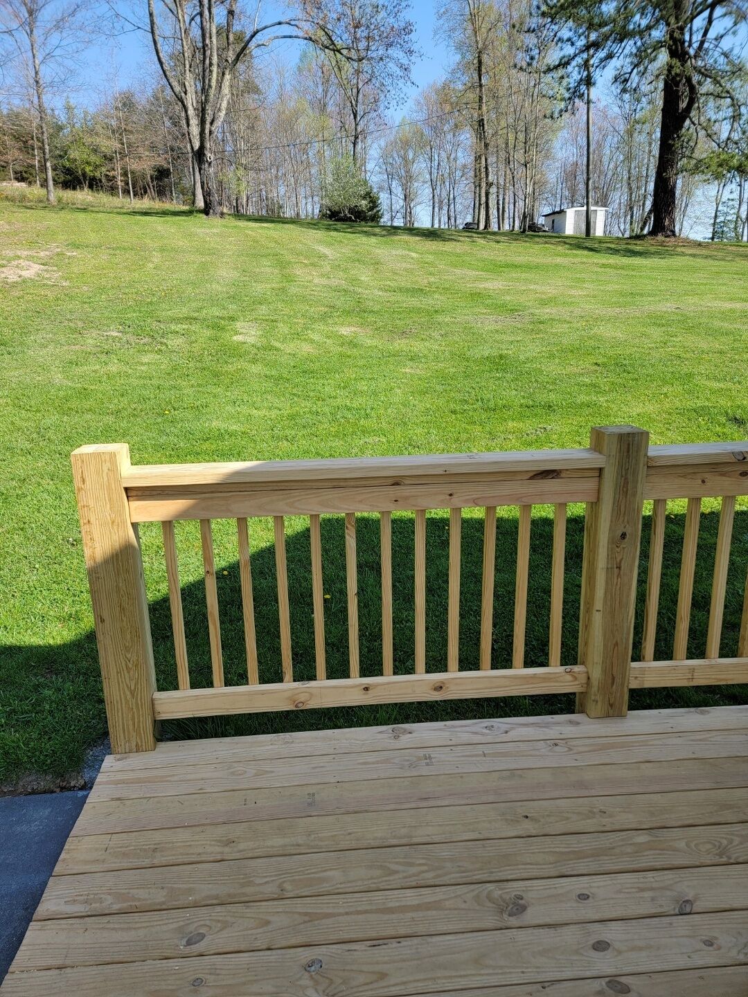 Una panchina di legno in un parco, sullo sfondo un'area erbosa e alberi.