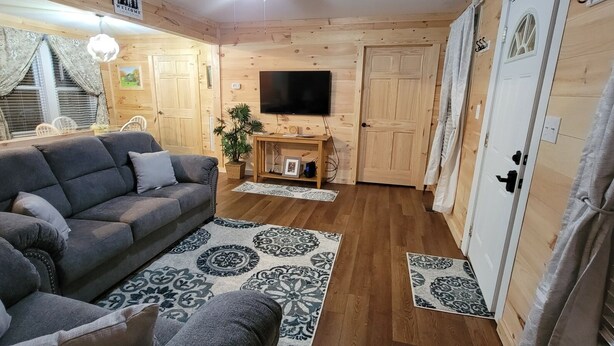 Ein gemütliches Zimmer mit einer Couch, einem Fernseher und einer Holztür.