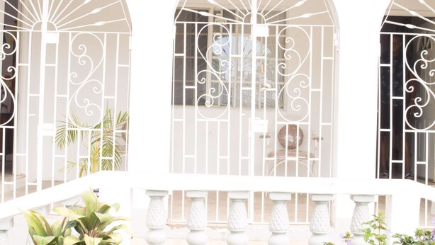 Fachada de edificio con ventanas de arco, barandillas blancas y balaustrada de piedra.
