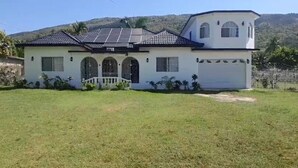Una casa con fachada blanca, un garaje y un techo con paneles solares.