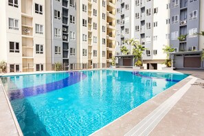 Een zwembad omringd door meerlaags woongebouwen met balkons en airconditioners.