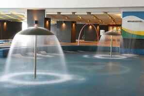 A modern indoor pool area with multiple water features, including fountains and a central water slide. - Penthouse Studio in the biggest Fitness & Family Complex - Fast Wifi/Netflix! (Quezon City)