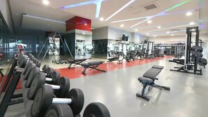 Une salle de sport équipée de divers appareils d’entraînement, notamment des haltères, des bancs et des machines de musculation.