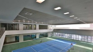 Un court de tennis intérieur à plusieurs niveaux et doté de grandes fenêtres.