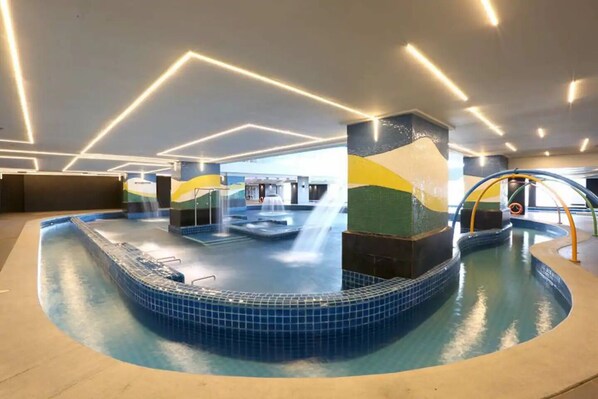 An indoor swimming pool with multiple water features and a modern design.
