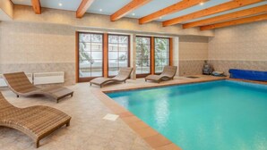 Un espace piscine comprenant des chaises longues, un jacuzzi et de grandes fenêtres.