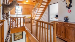 Un intérieur en bois avec une chambre à coucher située en mezzanine, un escalier et des bois de cerf fixés au mur.