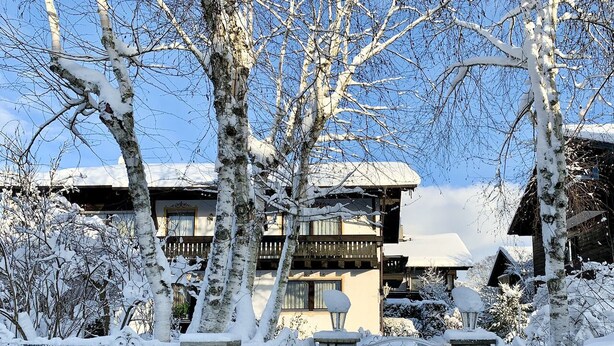Een gebouw bedekt met sneeuw, met een stenen ingang, houten balkons en een heldere lucht.