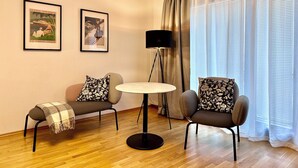 Un salon moderne comprenant un canapé, deux fauteuils, une petite table ronde et deux tableaux encadrés accrochés au mur.