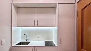 Une petite cuisine équipée d’un évier, d’un robinet et d’une cuisinière.