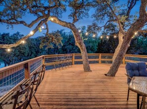 A wooden deck with a railing, a table, and chairs. - Rio Vista at Lightning Bug Springs (Uvalde)
