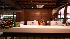 Un mostrador de recepción con un fondo de madera, un arreglo floral y un cartel que indica la política de registro.