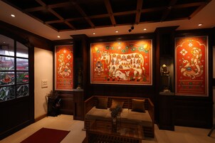 Una habitación de diseño tradicional, con un sofá, una mesa de centro de vidrio y un amplio mural en la pared con figuras religiosas.