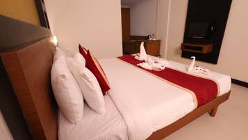 Habitación de hotel con una cama grande, cabecera de madera y una almohada roja decorativa.