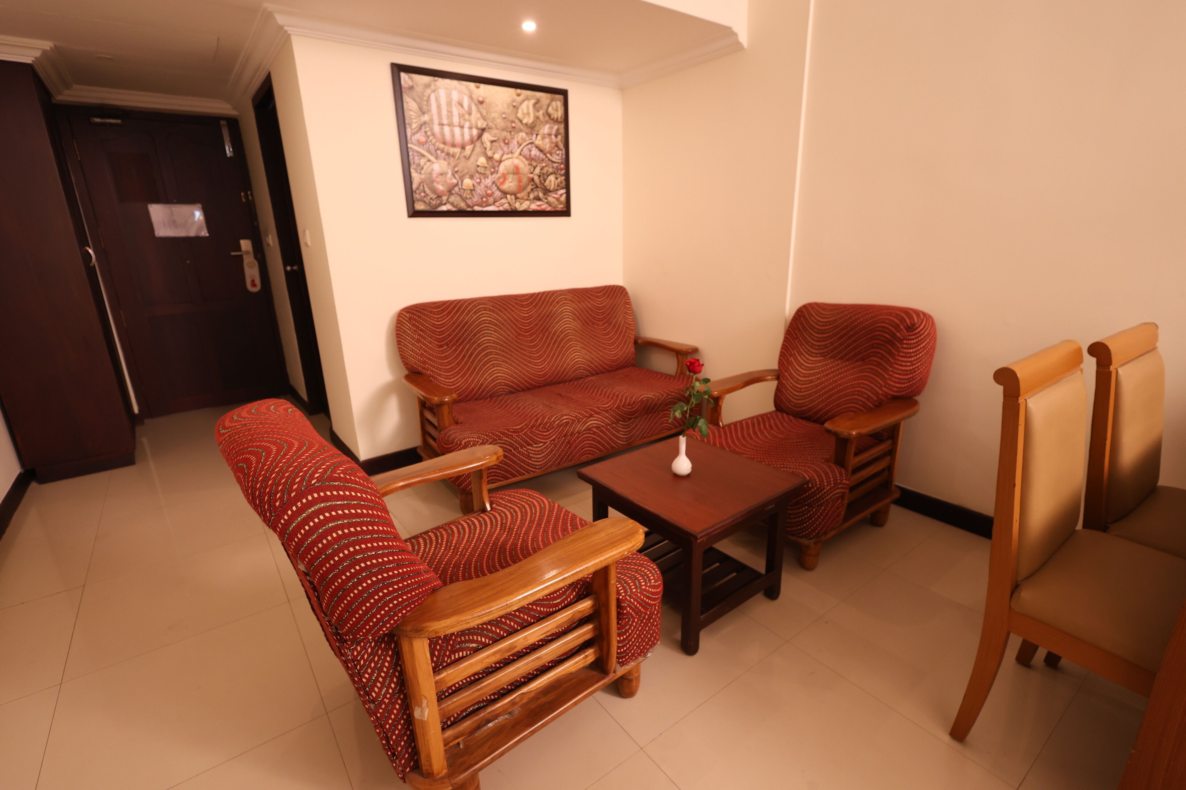 Una sala de estar con un sofá, dos sillones, una mesa de centro y un cuadro en la pared.