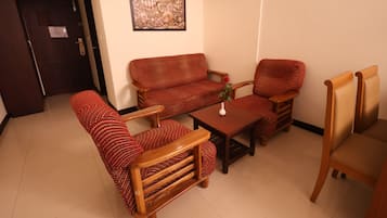 Una sala de estar con un sofá, dos sillones, una mesa de centro y un cuadro en la pared.