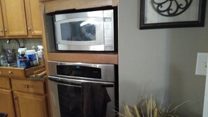 A kitchen with wooden cabinets, a microwave, an oven, and a potted plant.