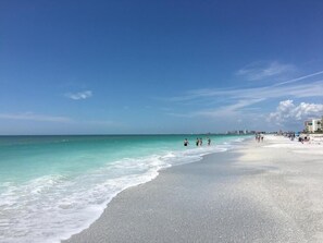 A beach with clear turquoise water, a wide sandy shore, and a few people walking. - Beachfront condo Belleair Beach (Belleair Beach)