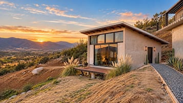 Una casa moderna con patio, ventanas amplias y vistas a las montañas.