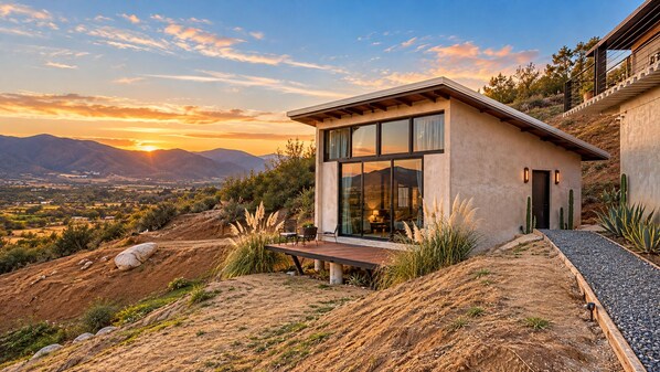 Una casa moderna con patio, ventanas amplias y vistas a las montañas.