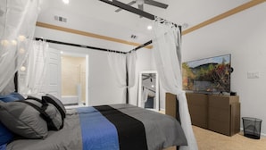 Ein Schlafzimmer mit einem Bett, einem Fernseher und einem Bild an der Wand.
