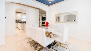 Ein moderner Essbereich mit einem weißen Tisch, goldenen Stühlen und einer Chandelier.
