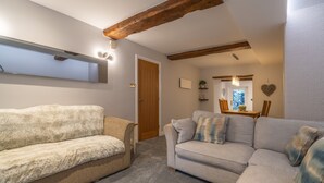 A cozy living room with a wooden ceiling, a sofa, and a coffee table. - Laburnum Cottage -  Windermere, with Parking (Windermere)