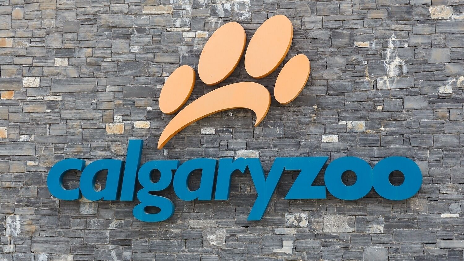 Een bord voor de Calgary Zoo met een logo van een pootafdruk en de naam in blauwe letters.