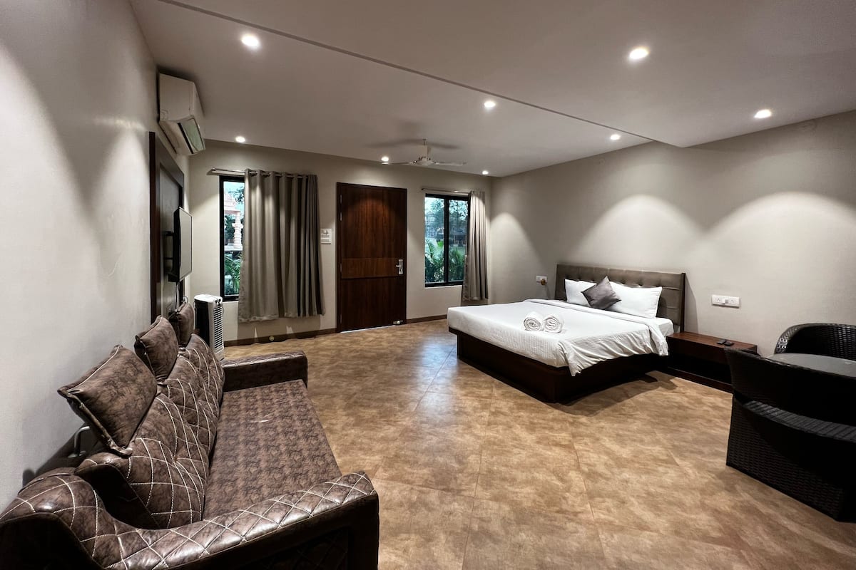 Une chambre d’hôtel moderne avec un grand lit, un canapé, une petite table et un téléviseur.