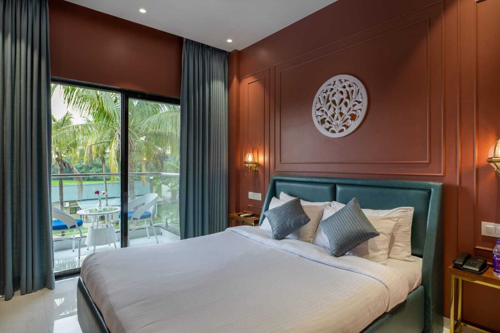 Une chambre d’hôtel avec un grand lit, une vue sur une piscine et des palmiers, et un élément décoratif mural.