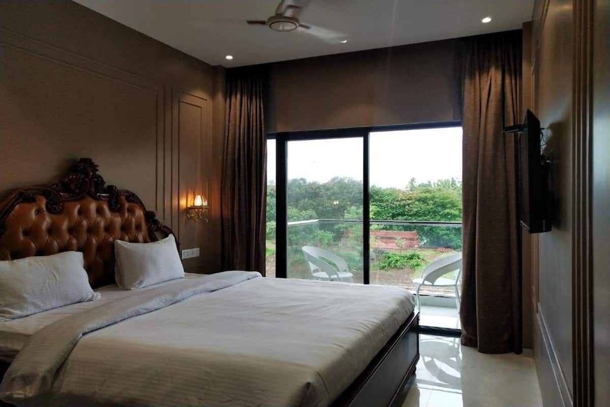 Une chambre avec un grand lit, un ventilateur de plafond et une vue sur la verdure environnante.