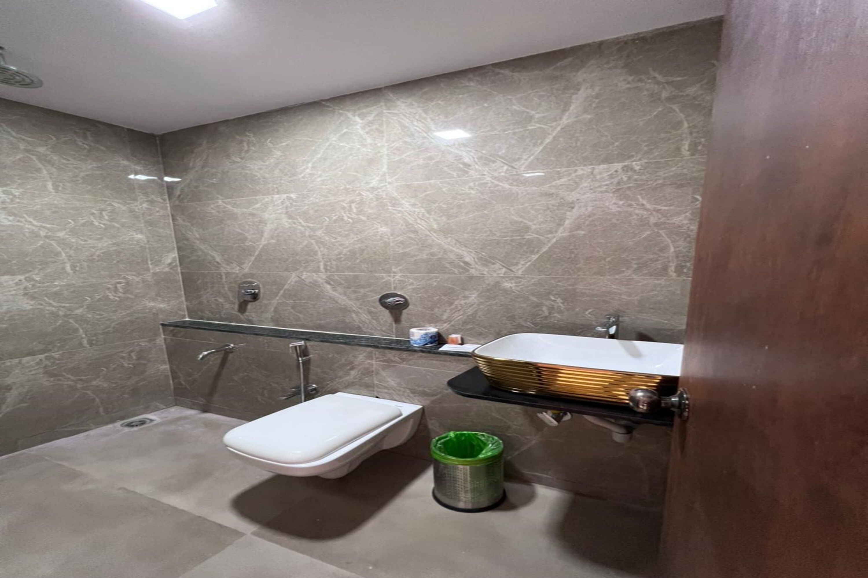 Ein Badezimmer mit Toilette, einer Glasdusche, einem Waschbecken mit Waschtisch und einem Mülleimer.