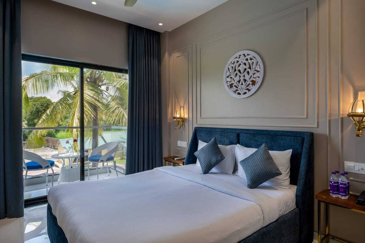 Une chambre d’hôtel avec un grand lit, une vue sur une piscine et des palmiers, et un élément décoratif mural.