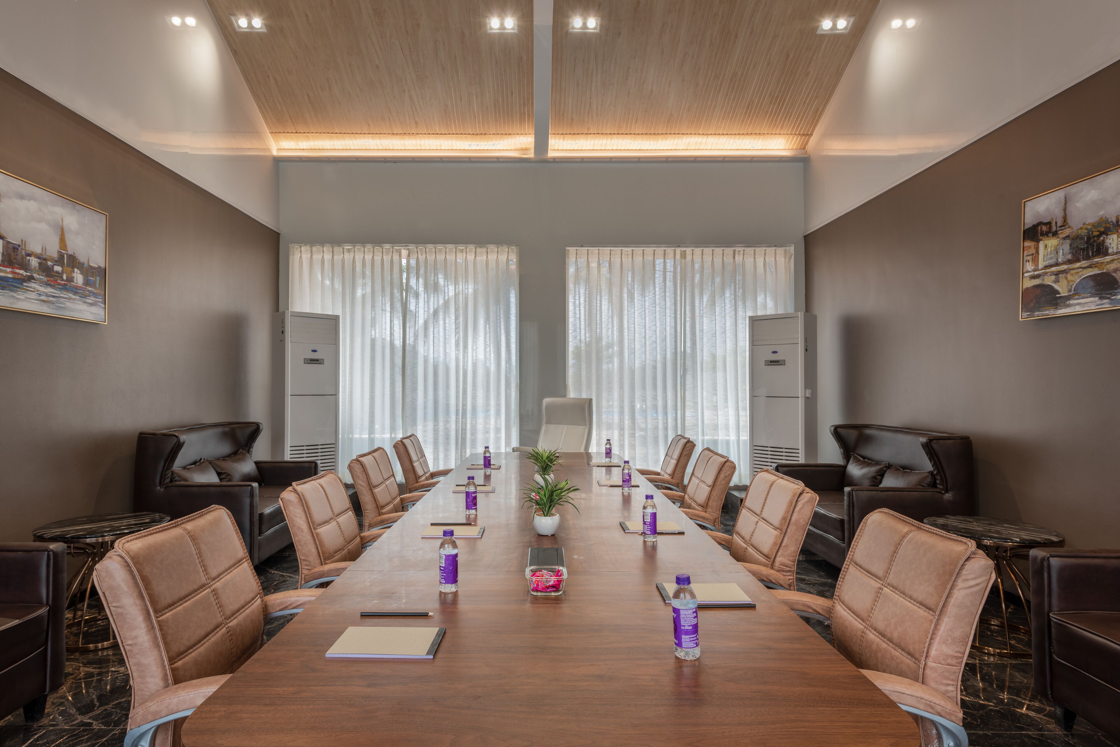 A conference room with a long table, leather chairs, and a potted plant.