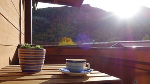 A wooden table with a striped pot and a blue and white cup on a wooden deck overlooking a forested hillside. - Apartment Bergzeit- 2 Per. 42sqm, 1 bedroom, wood stove, balcony, WLAN (Oberwössen)
