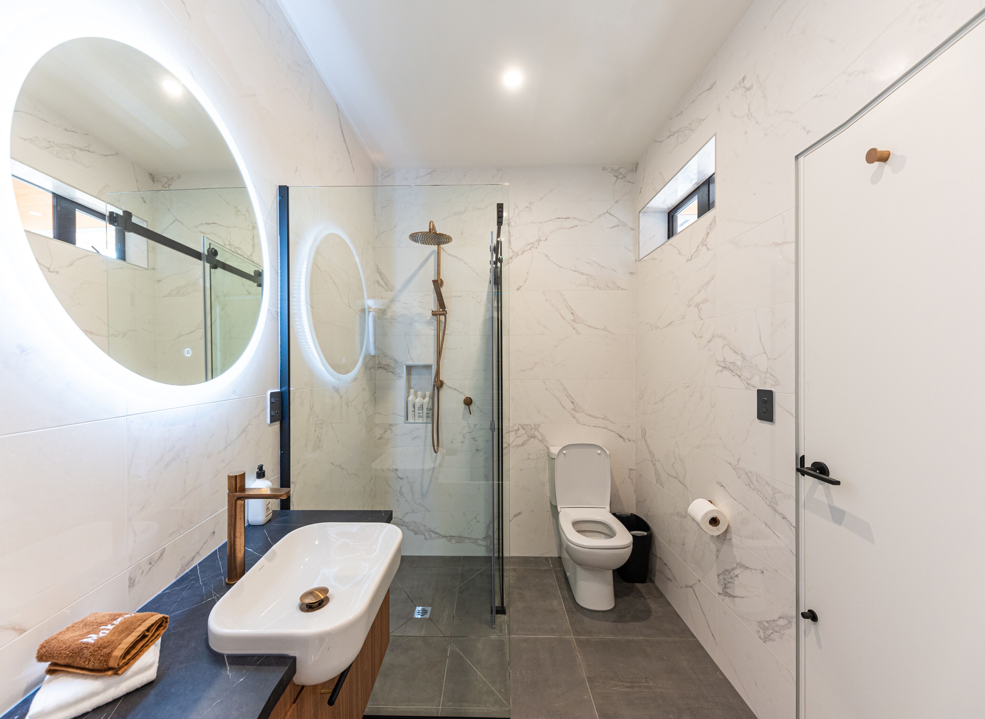 A modern bathroom with a freestanding bathtub, a toilet, and a shower area.