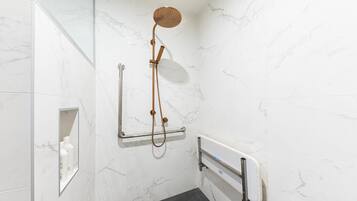 A modern bathroom with a shower, grab bars, and a handrail.