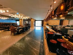 Interior moderno de restaurante con suelo de mármol, varias mesas de comedor y una zona de bar con taburetes.