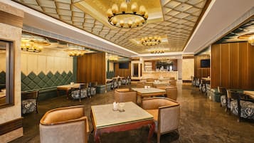 Un restaurant spacieux avec de hauts plafonds, des lustres et différents types de sièges, notamment des banquettes et des tables.