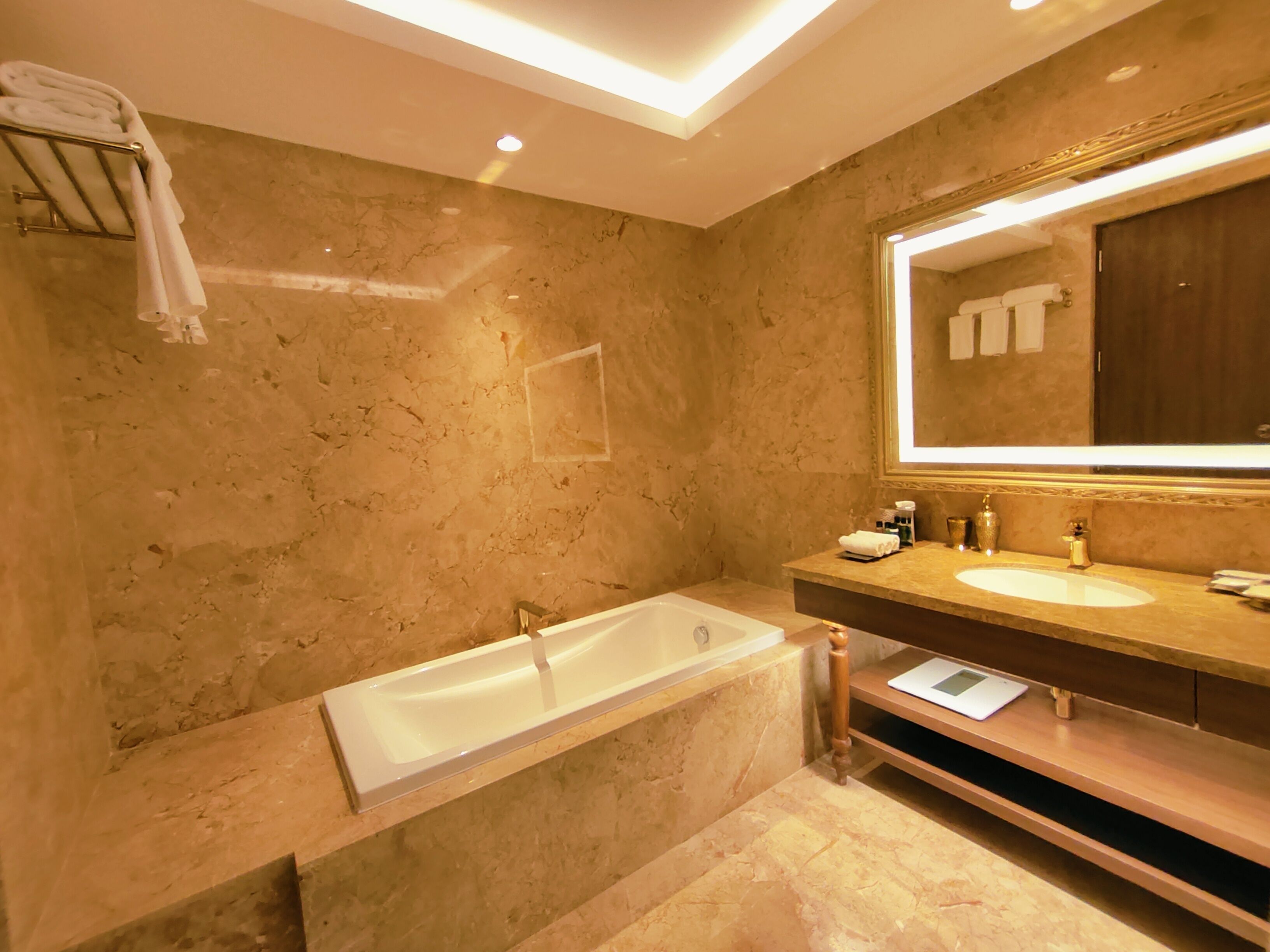 A modern bathroom with a large bathtub, a vanity with a mirror, and a towel rack.