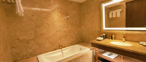 A modern bathroom with a large bathtub, a vanity with a mirror, and a towel rack.