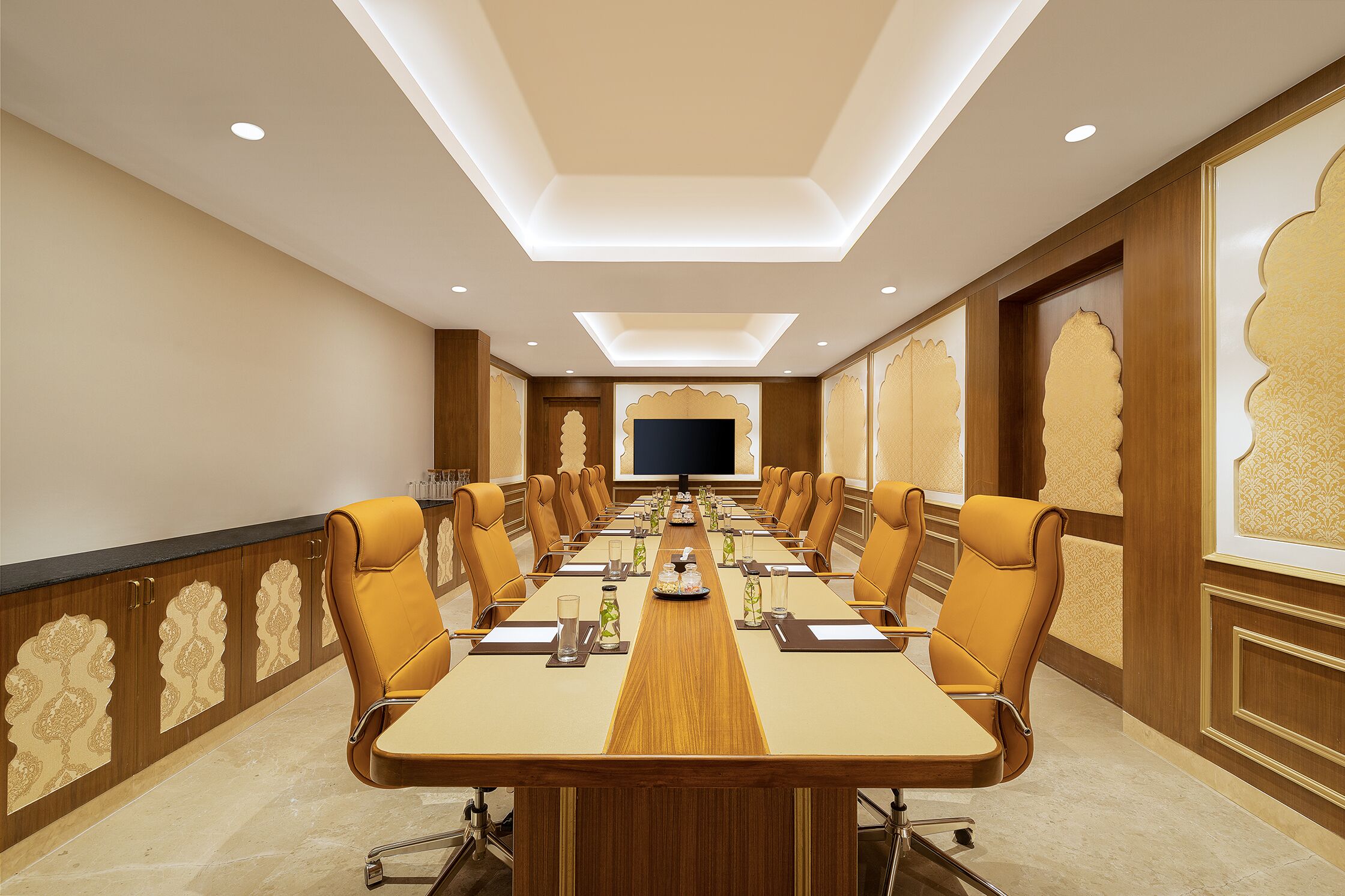 A conference room with a long table, chairs, and a television screen.