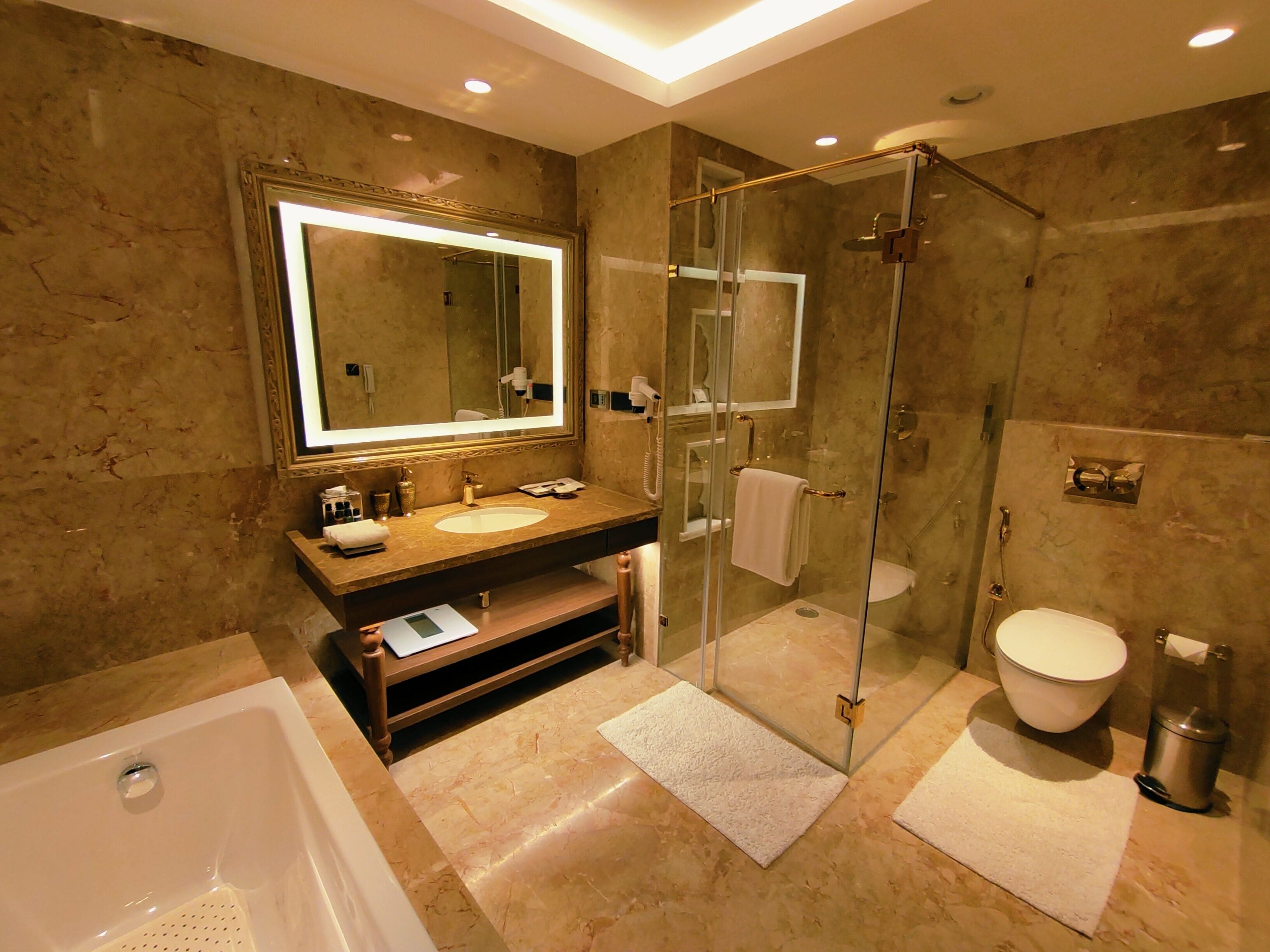 A modern bathroom with a glass-enclosed shower, a large mirror, and a bathtub.