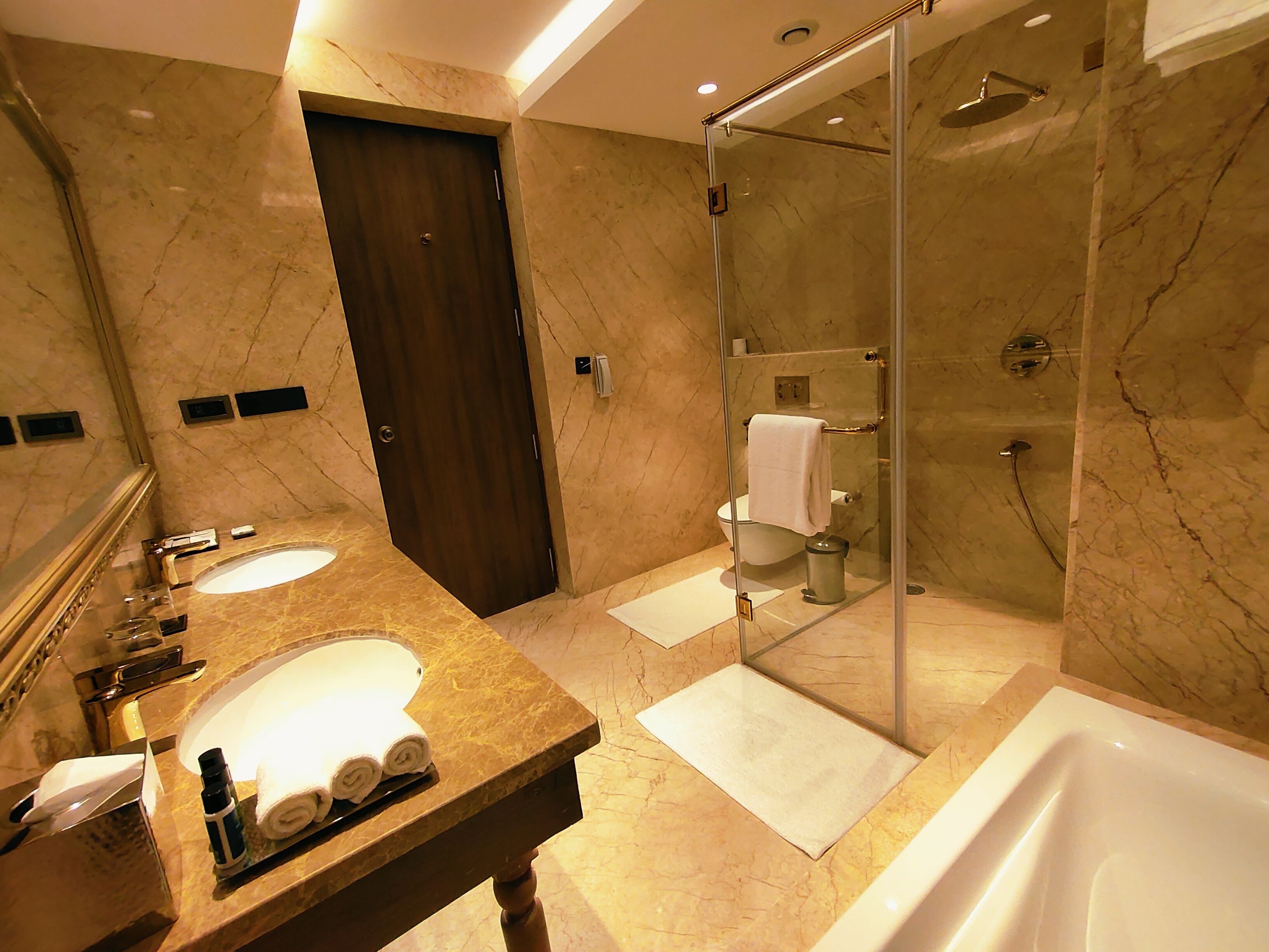 Une salle de bain moderne avec un comptoir en marbre, une douche à parois de verre et un espace lavabo séparé.
