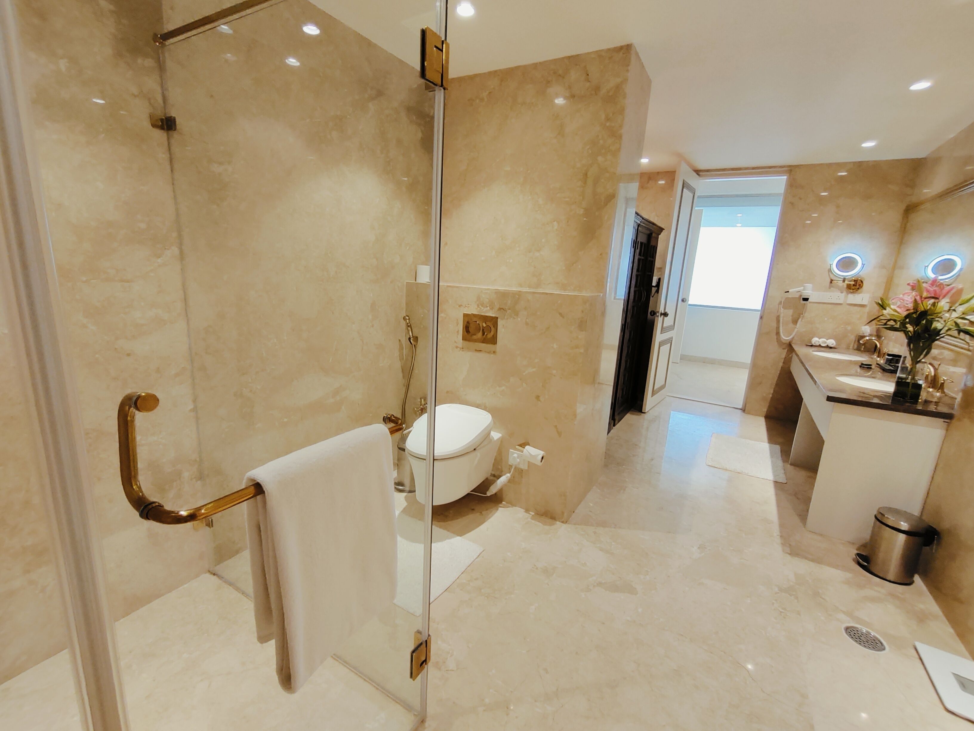 Een moderne badkamer met een glazen douchecabine, toilet en een wastafel met spiegel.