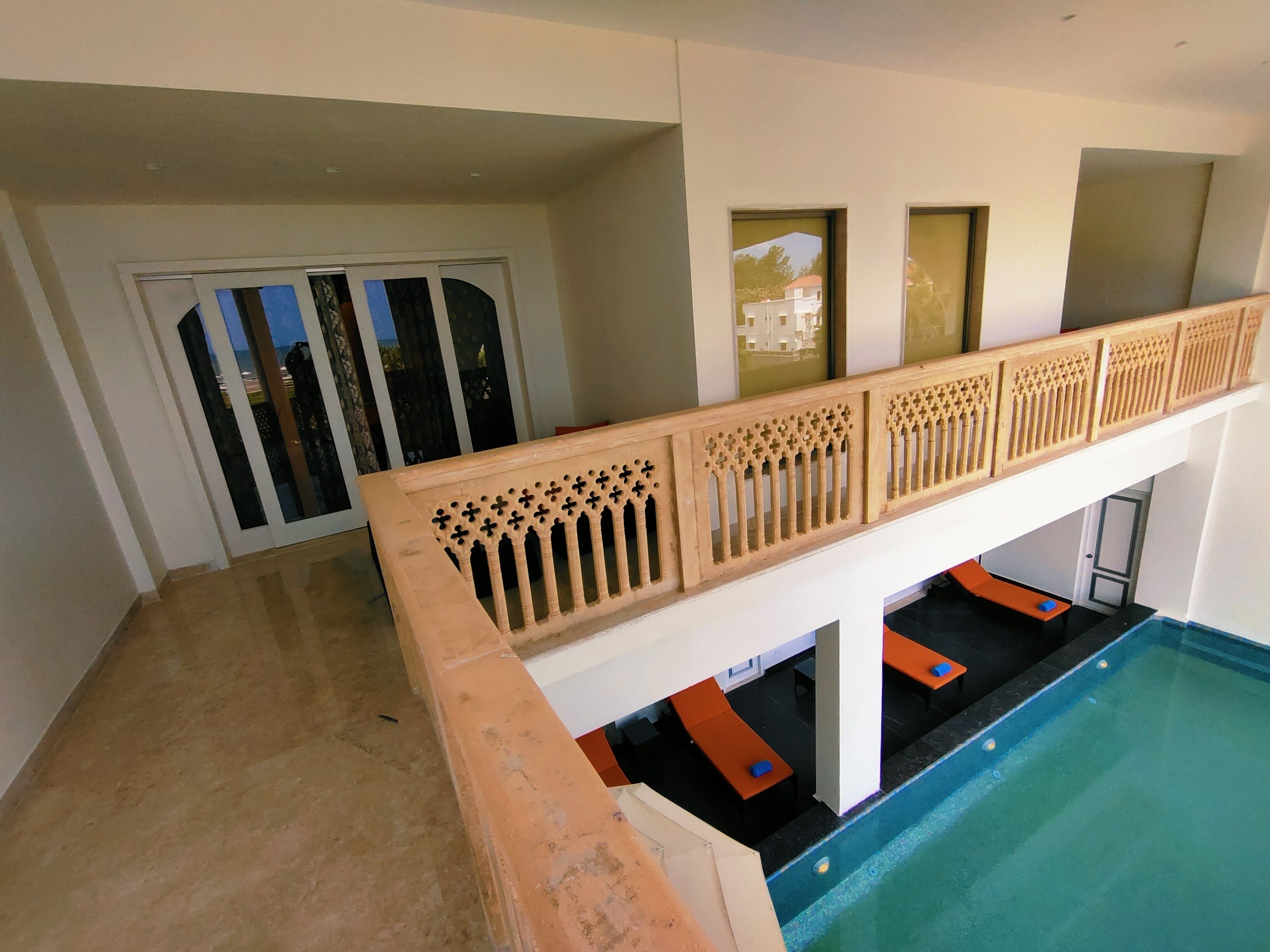 A pool area with a wooden railing, a door with glass panels, and a view of a building outside.